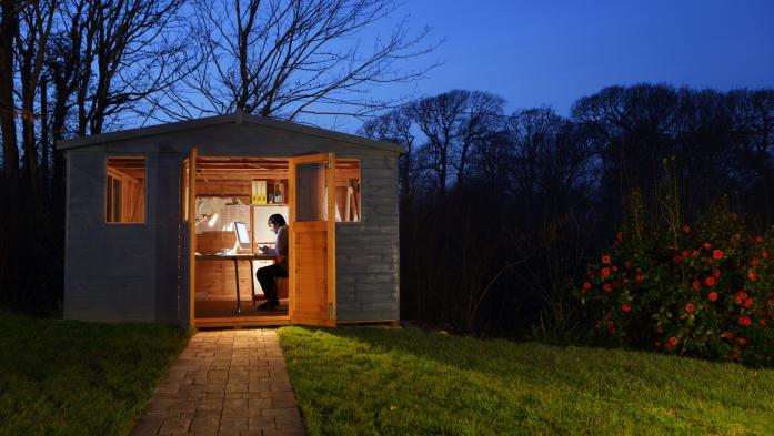 Many inside the door of a backyard shed using it as an office